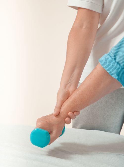 Ein Phystiotherapeut trainiert mit einem Senior mit einer Kurzhantel.